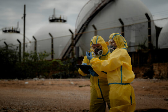 Hazardous chemical contamination inspection concept. Environmental scientists in protective suits collecting polluted water samples near industrial wastewater area. pollution, hazmat, safety,