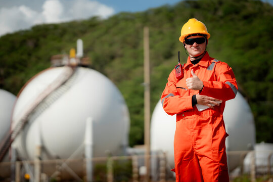 professional engineer, worker, technician use clipboard discuss work, factory plant industry at a gas storage facility. protective uniforms and helmets. industry, engineer, safety
