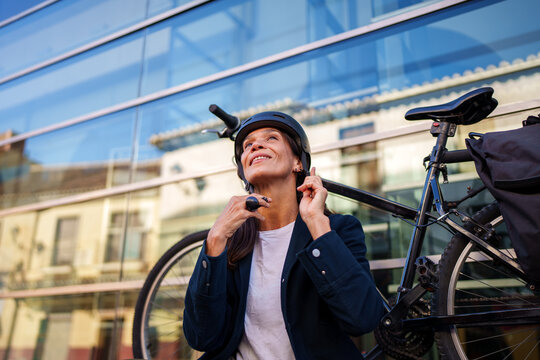 Hispanic woman adjusting helmet next to bicycle in M&aacute;laga city