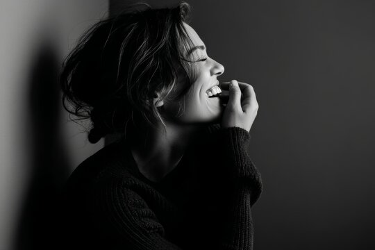 Portrait of a content woman in her 30s laughing in bare monochromatic room