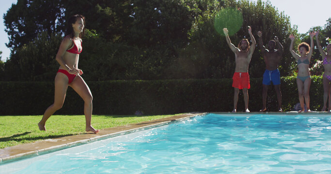 Diverse group of friends having fun jumping into a swimming pool