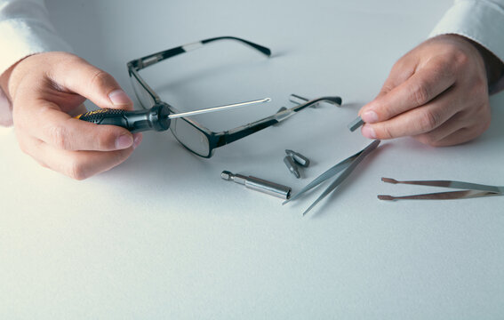Close-up Of A Businessman Repairing Glasses With Screwdriver