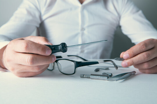 Close-up Of A Businessman Repairing Glasses With Screwdriver