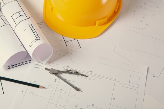 Standard construction safety equipment including hardhat, glasses, pen and blueprints.