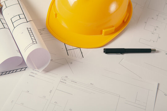 Standard construction safety equipment including hardhat, glasses, pen and blueprints.