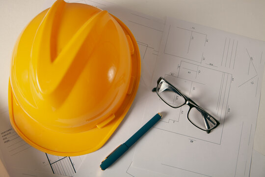 Standard construction safety equipment including hardhat, glasses, pen and blueprints.