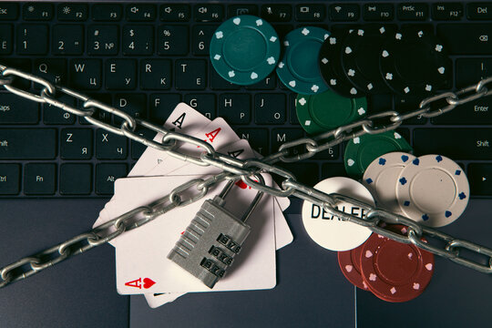 Poker chips, combination lock and playing cards on the laptop keyboard