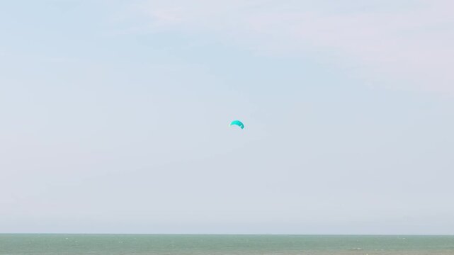 Two colorful kites flying above the sea under a pale cloudy sky