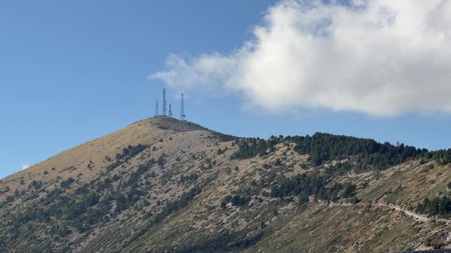 Mountain Peak With Communication Towers Rising Above Forested Slopes