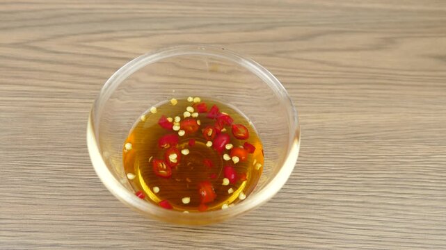 Red chili peppers fish sauce glass bowl on wood background.
Dipping Prik Nam Pla traditional thai restaurant.
top view