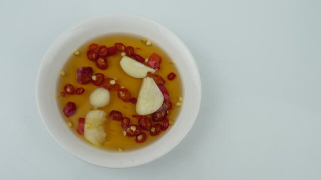Red chili peppers fish sauce glass bowl on wood background.
Dipping Prik Nam Pla traditional thai restaurant.
top view