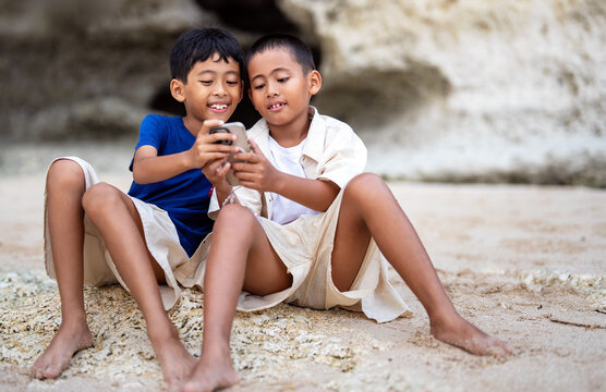 Asian brothers making discoveries and creative ideas on smartphone on summer vacation