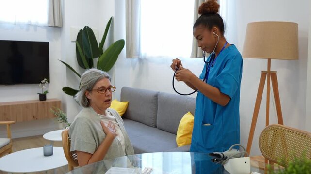 Caring latina home health nurse using stethoscope to listen to lungs of senior woman during medical checkup at residence
