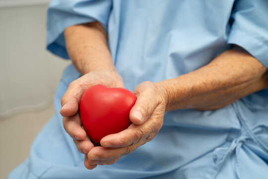 Asian senior patient woman holding red heart for health in hospital.