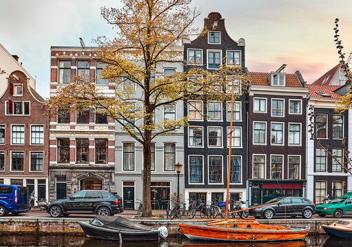 Amsterdam, Netherlands. Vintage brick canal houses and historic buildings line the waterfront. Classic European architecture with traditional boats and bicycles captures a scenic retro city vibe.