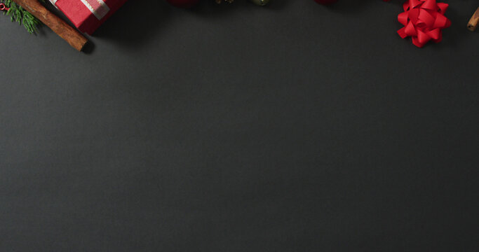 Image of christmas decorations and presents with pine cones and copy space on black background
