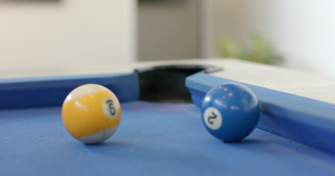 9 and 2 billiard balls are sitting on blue-felt pool table near corner pocket, reflections glinting