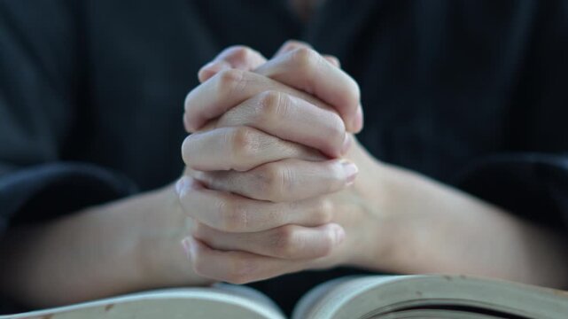 holding hands with praying book. A Christian's devout prayer time, placing both hand on the Bible and offering earnest in silence. religion concept.