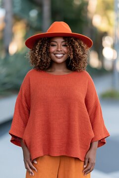 Confident smiling woman in orange hat and textured sweater outdoor portrait for fashion banner and lifestyle background
