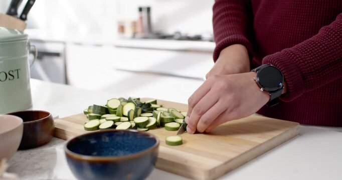 African American man slicing zucchini on cutting board then depositing trimmings in compost bin