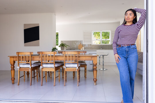 African American woman leaning against doorway while looking to side near table, copy space