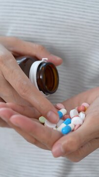 close up woman hand holding a medicine, with pours the pills out of medicine bottle. Stop drug use Taking Medication Caring for the health care medical concept.