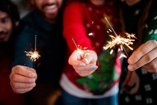 Friends and family holding sparklers at a festive Christmas holiday celebration, smiling and enjoying a joyful New Year party