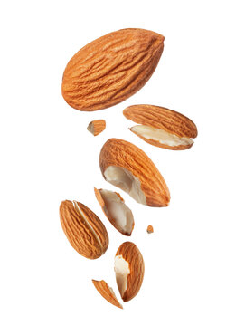 Flying whole and broken almond nuts with pieces falling in motion, creative levitation food photography isolated on a white background