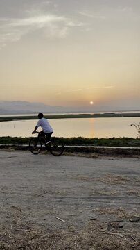 Cyclist Riding by the Lake at Sunset