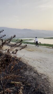 Cyclist Riding Along Lake at Sunset
