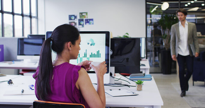 businesswoman drinking coffee sitting at desk with computer in office