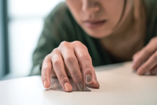 A focused woman inspects her manicured nails with various shades, symbolizing the deep connection between beauty choices and personal identity in a modern context.