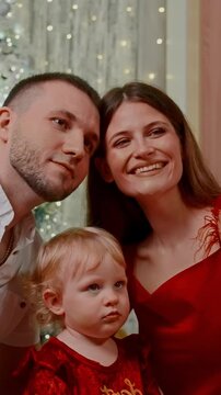Cherished Family Moments Captured: A Joyful Celebration of Togetherness with a Loving Couple and Their Adorable Child in Front of a Festive Backdrop