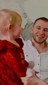 Heartwarming Moments: A Young Child in a Festive Red Outfit Interacts with a Smiling Adult in a Joyful Setting Full of Love and Togetherness.