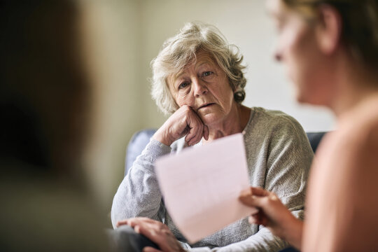 An elderly woman listens intently during a discussion, reflecting her thoughtful demeanor and the importance of engagement in conversations about personal topics or decisions.