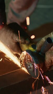 A Skilled Worker Using a Power Tool to Cut Metal, Creating Sparks in a Workshop Environment during Evening Hours with Safety Gear