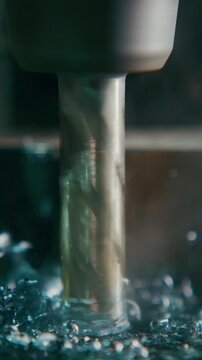 Close-up of a drilling tool in action, creating metal shavings as it cuts through material, accompanied by splashes of water to cool and lubricate the process.