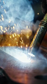 Captivating Close-Up of Welding Process: Sparks, Smoke, and Bright Flame Illuminate Metalwork in This Dynamic Industrial Setting