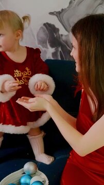 Joyful Holiday Moments: A Charming Mother and Her Child Decorate for Christmas with Colorful Ornaments and Festive Laughter in a Cozy Setting