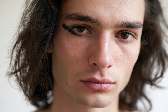 A captivating contemporary portrait of a young man with long, dark hair, presenting an emotional and introspective gaze that invites viewers to dive deep into the essence of his character.