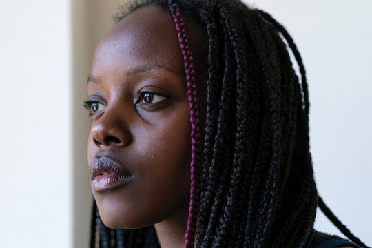 A close-up portrait of a young woman with braided hair, reflecting deeply with an expression that conveys her inner thoughts and emotions captured in beautiful light.