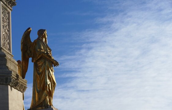 Statue of and golden angel with big wings high in the blue sky near Zagreb cathedral, statue and architecture background