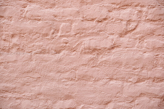 Rough pink stucco wall with uneven plaster texture