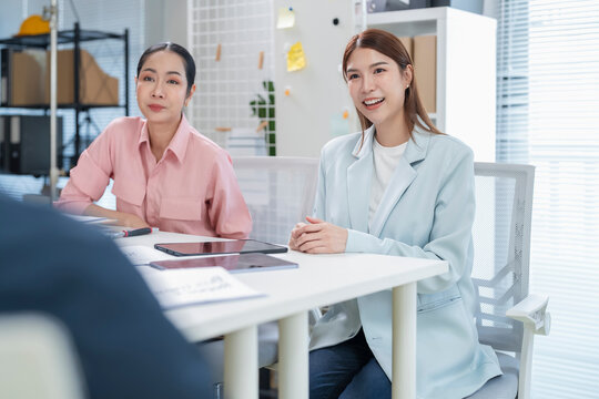 Smiling Asian HR recruiters welcoming and listening to job candidate during friendly job interview at office table, positive recruitment and hiring concep