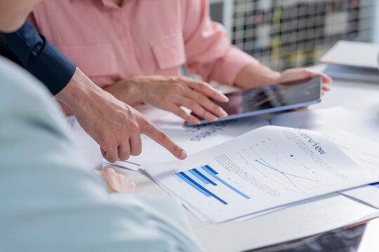 Close up of business team hands reviewing business proposal and business analysis documents with stylus and digital tablets on office table during meeting