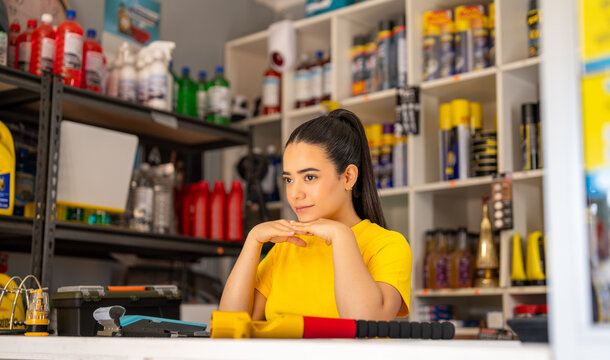 Auto parts shop assistant smiling behind a retail counter lined with automotive supplies