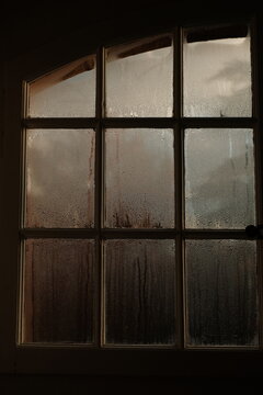 Condensation on Grid Window Panes in Dimly Lit Room