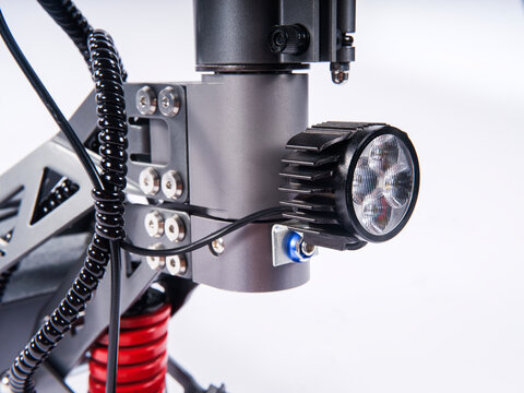Close-up of electric scooter front LED headlight mounted on steering stem, isolated white background