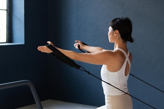 Woman Pulling Pilates Reformer Straps with Arms Extended Forward