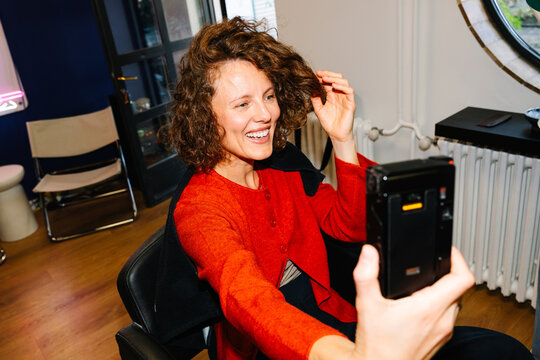 Woman taking self portrait with film camera at salon